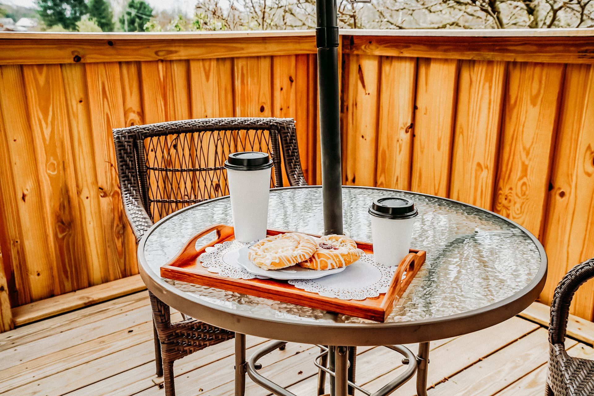 Outdoor patio scene with a glass-top table, two coffees, and a tray with toast.