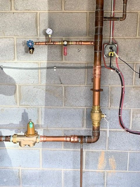 Copper plumbing pipes and valves mounted on a cinder block wall