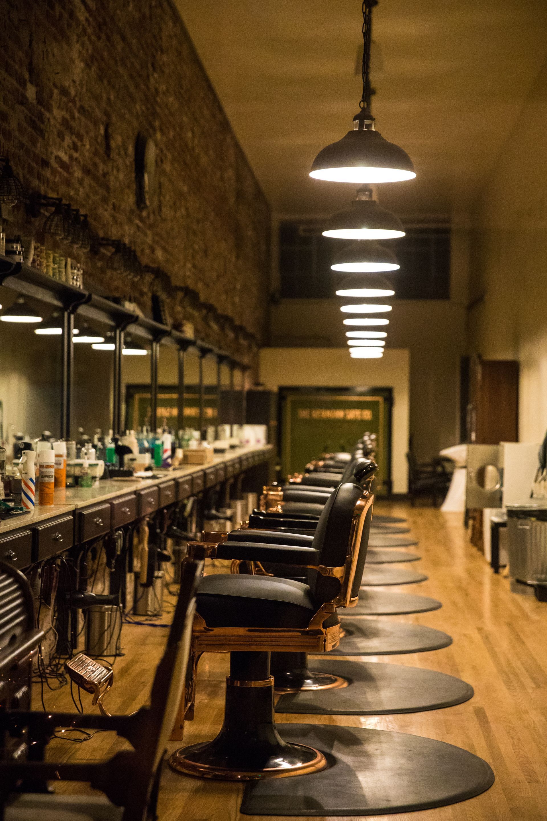 Interior of a vintage barbershop, featuring barber chairs, mirrors, and overhead lighting.