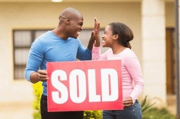A man and a woman are giving each other a high five while holding a sold sign. A man and a woman are giving each other a high five while holding a sold sign.