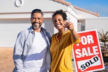 A man and a woman are holding the keys to their new house. A man and a woman are holding the keys to their new house.