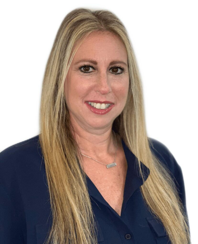 A woman with long blonde hair is wearing a blue shirt and smiling.