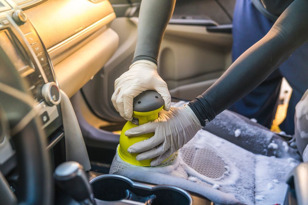 A Person Is Cleaning The Interior Of A Car With A Sander — Townsville Car Care Centre In Aitkenvale, QLD