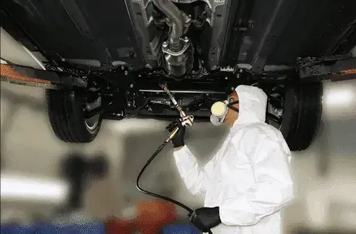 A Person Is Spraying Lubricant Under The Car — Townsville Car Care Centre In Aitkenvale, QLD