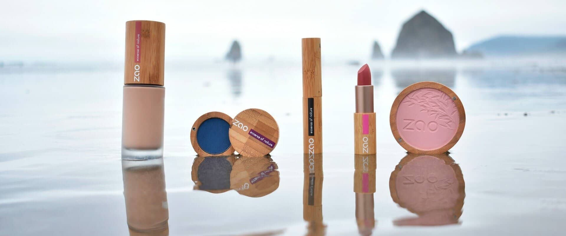 A group of makeup products are sitting on a table in front of a body of water.