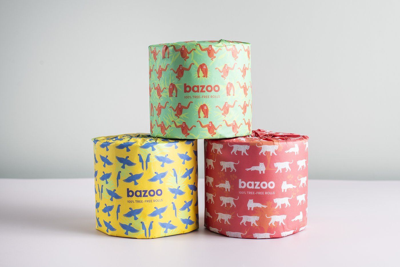 Three rolls of bazoo toilet paper are stacked on top of each other on a table.