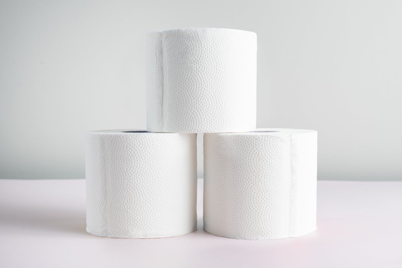 Three rolls of toilet paper are stacked on top of each other on a table.