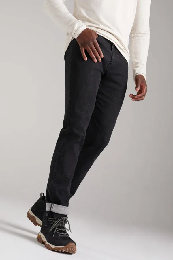 A man wearing a white shirt and black jeans is standing with his hands on his hips.