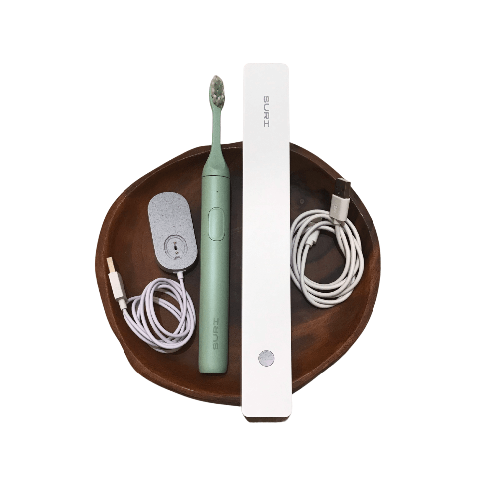 a green electric toothbrush is sitting on a wooden tray .