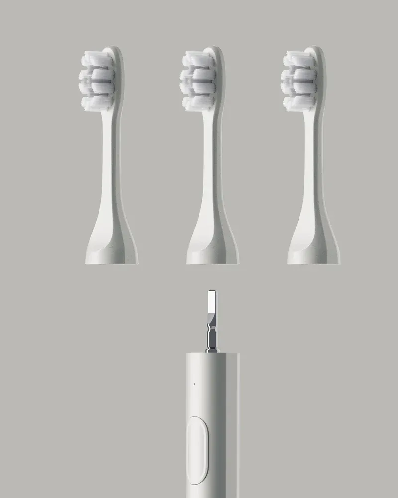 three toothbrush heads are attached to a white electric toothbrush .