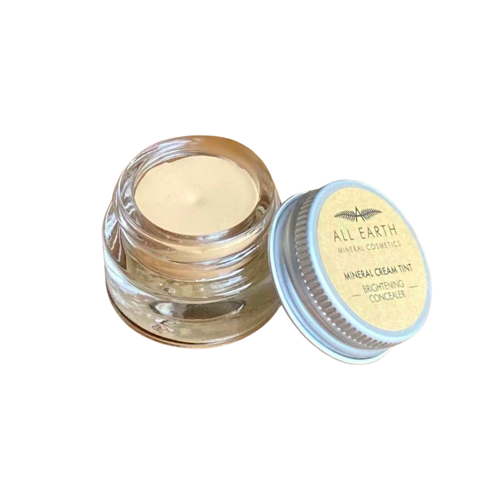 A small jar of concealer is sitting on a white surface.