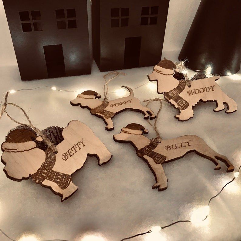 A set of wooden dog christmas tree ornaments personalised with the names betty and billy on them