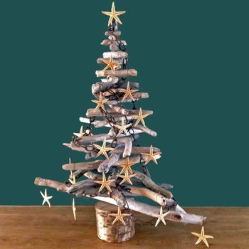 A christmas tree made of driftwood and starfish is sitting on a wooden table.