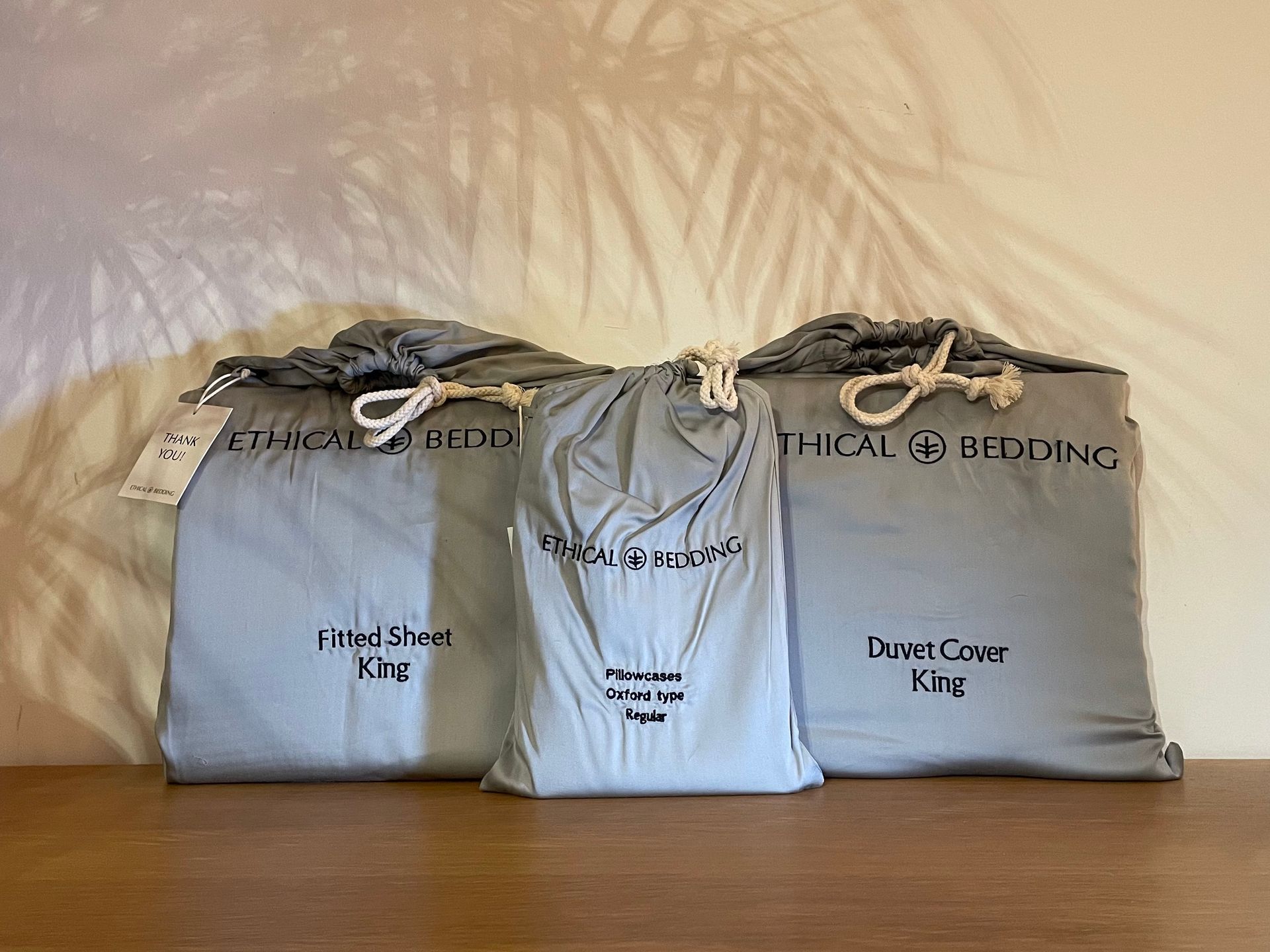 Three bags of Ethical Bedding are sitting on a wooden table.