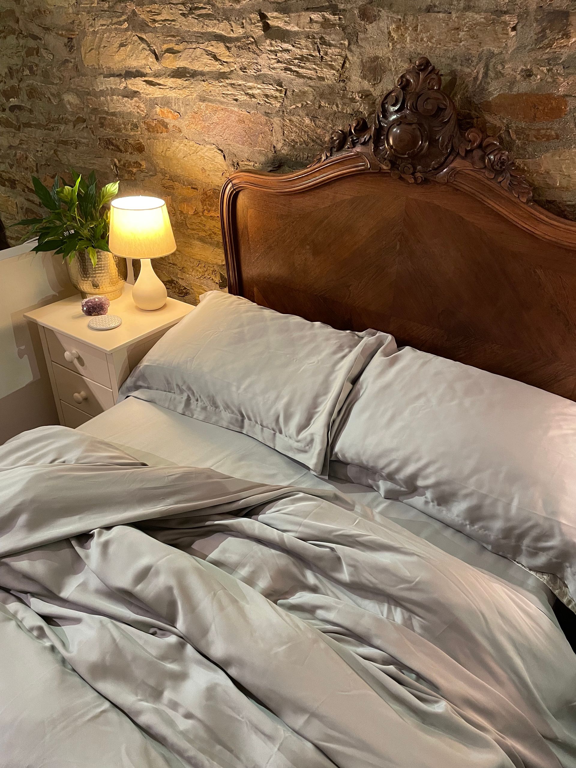 a bed with eucalyptus silk bed sheets and a lamp on the nightstand next to it
