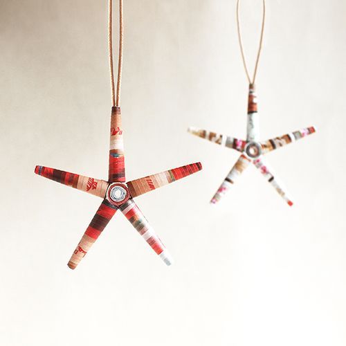 Two christmas star ornaments are hanging from a string on a white surface.