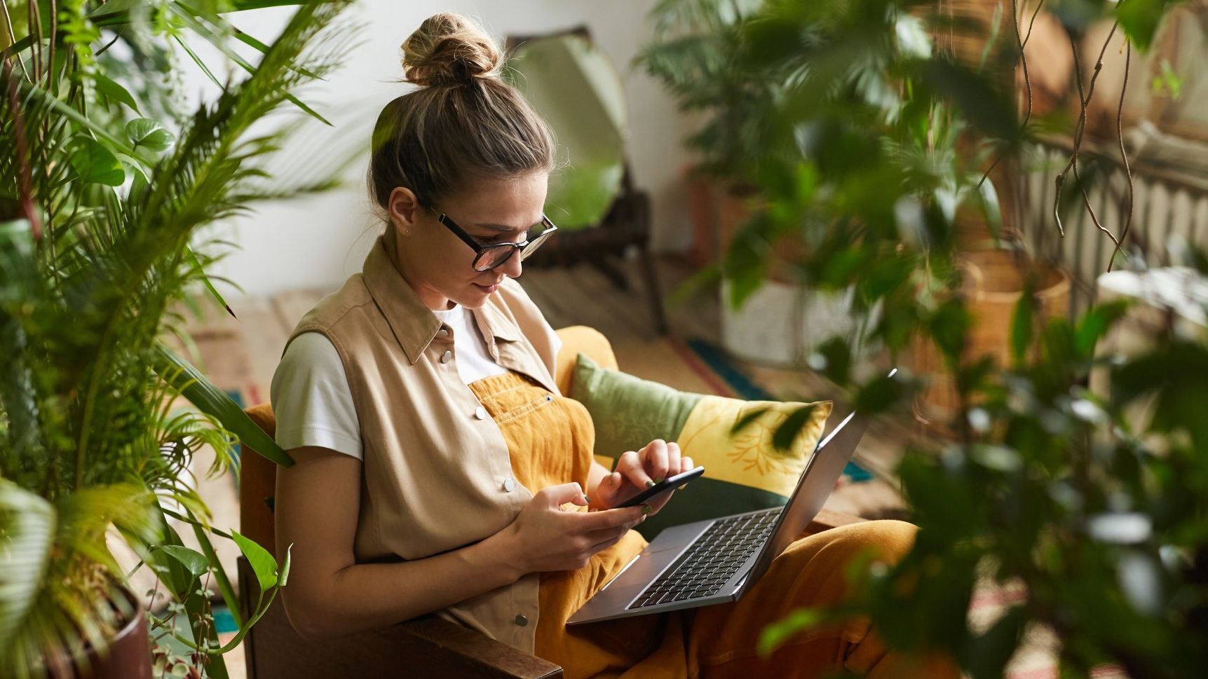 a woman sits in a chair with a laptop and a cell phone
