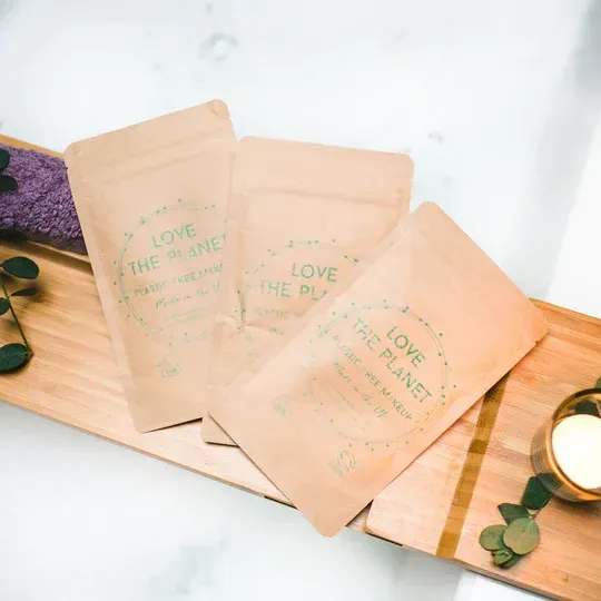 Three bags of love the planet are sitting on a wooden tray.
