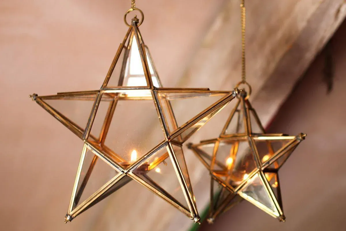 Two brass stars with candles inside of them hanging from the ceiling
