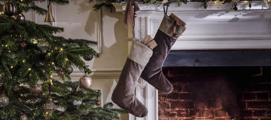 Two christmas stockings are hanging on a mantle next to a christmas tree.