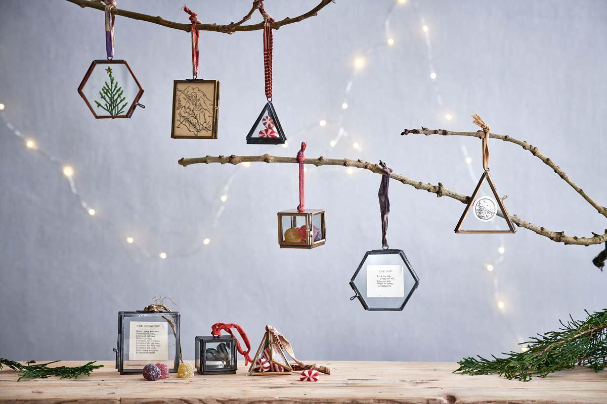 A wooden table topped with christmas decorations hanging from a tree branch.
