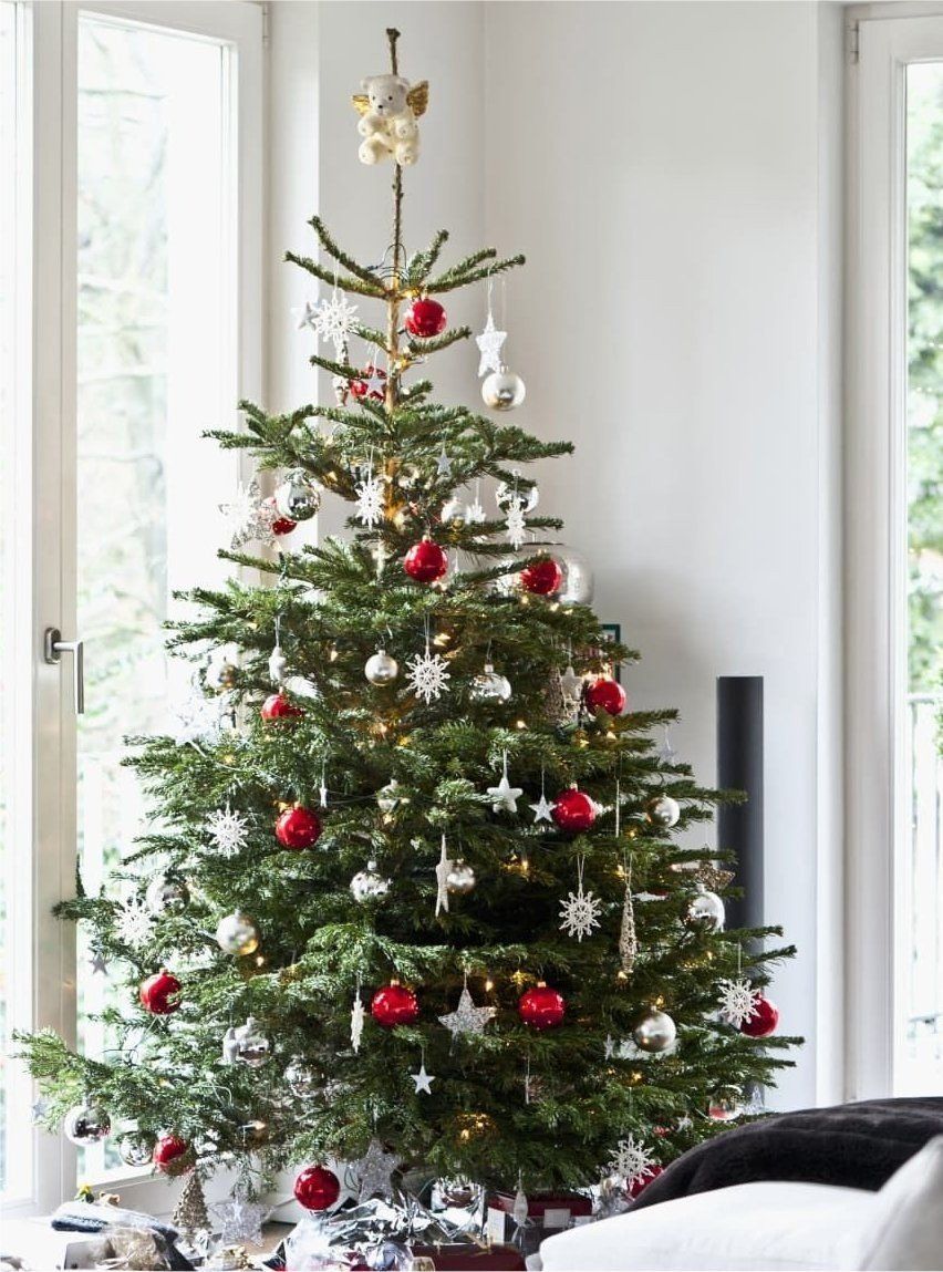 A christmas tree in a living room with red and white ornaments