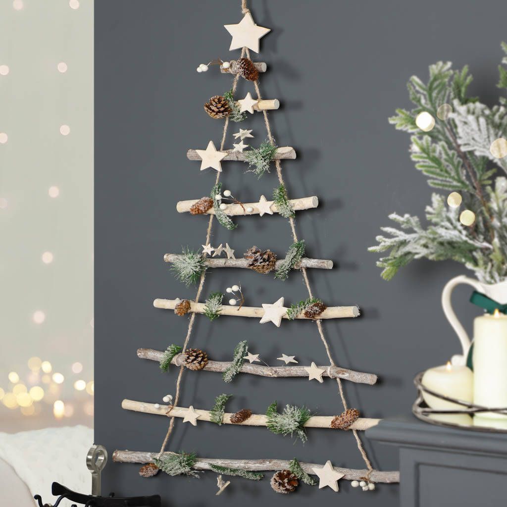 A christmas tree made out of branches is hanging on a wall