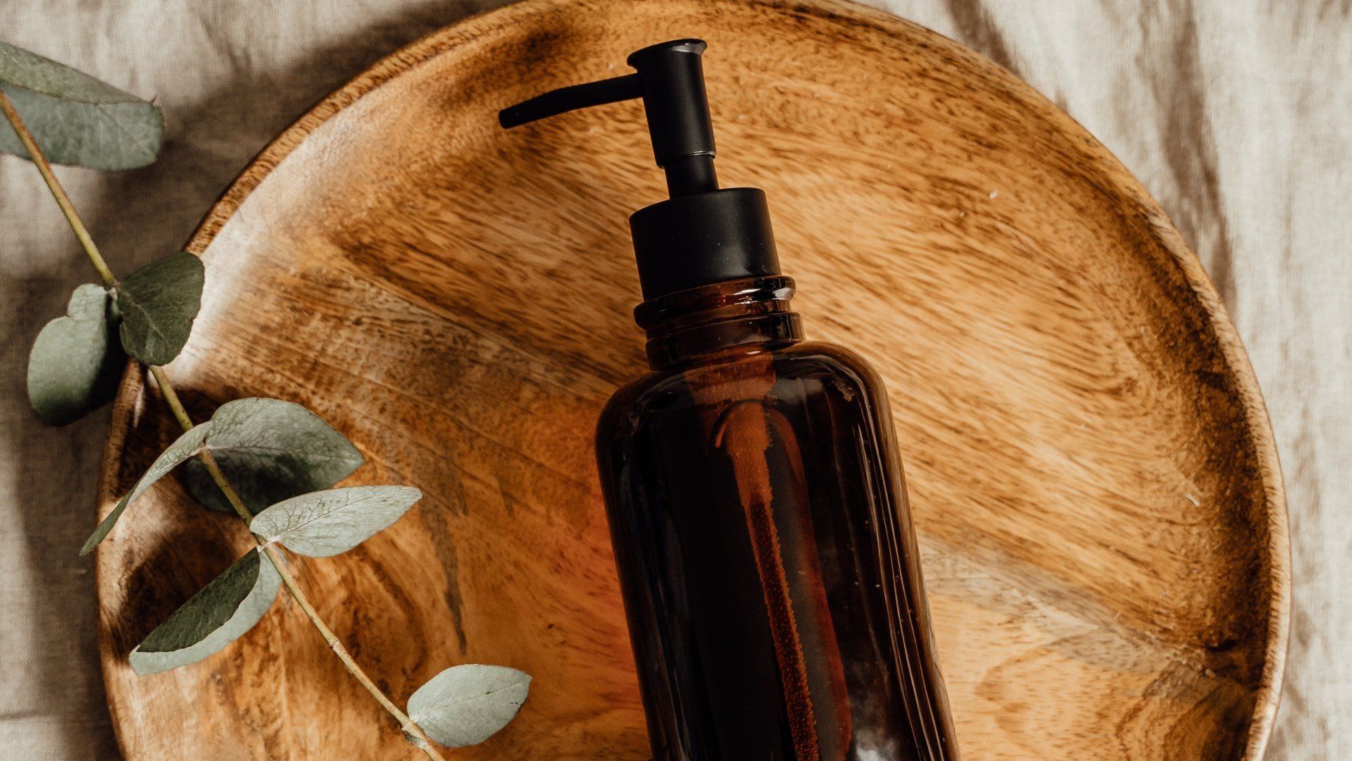 A bottle of soap is sitting on a wooden tray.