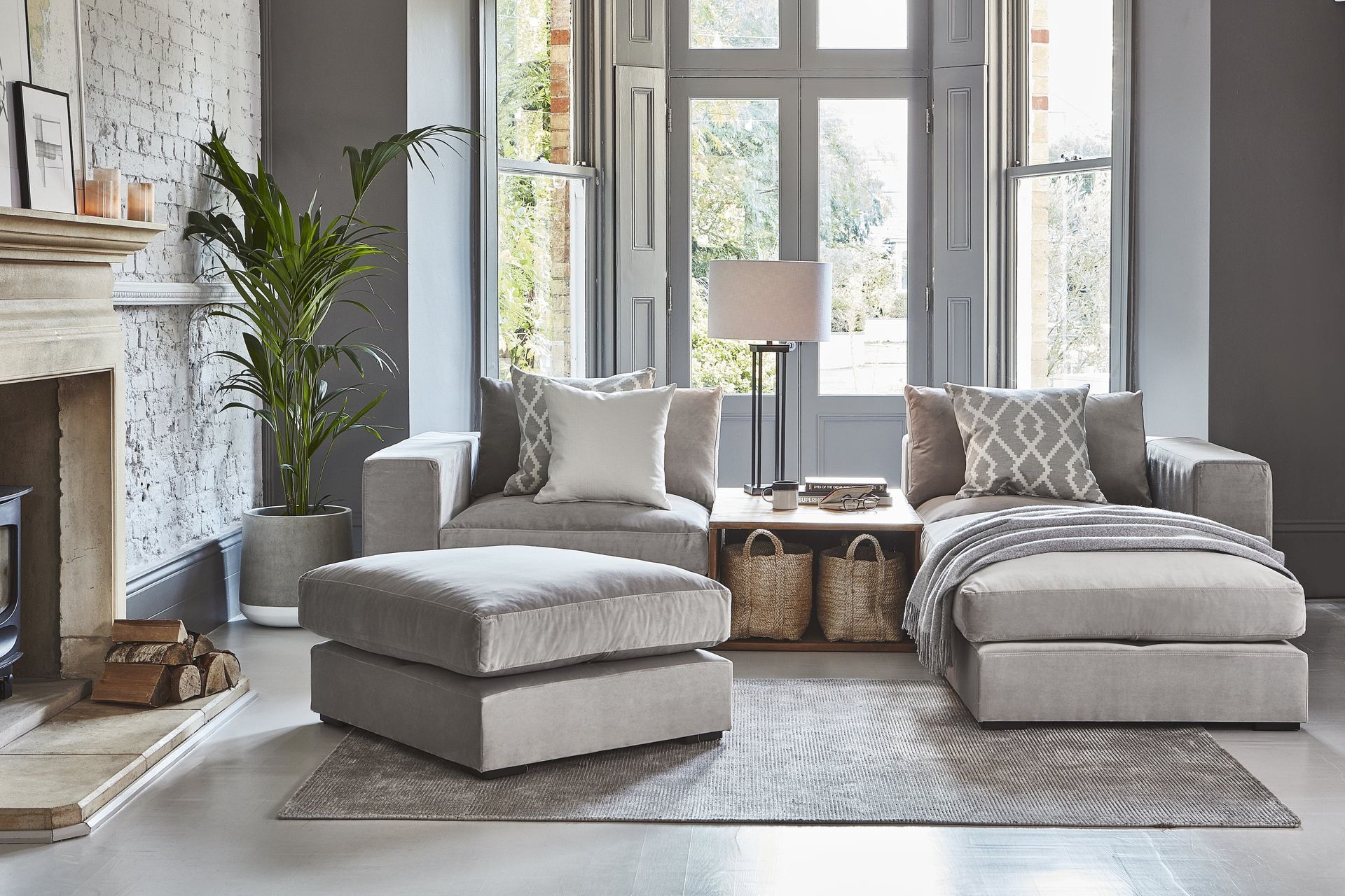 A living room with a couch , ottoman , and fireplace.