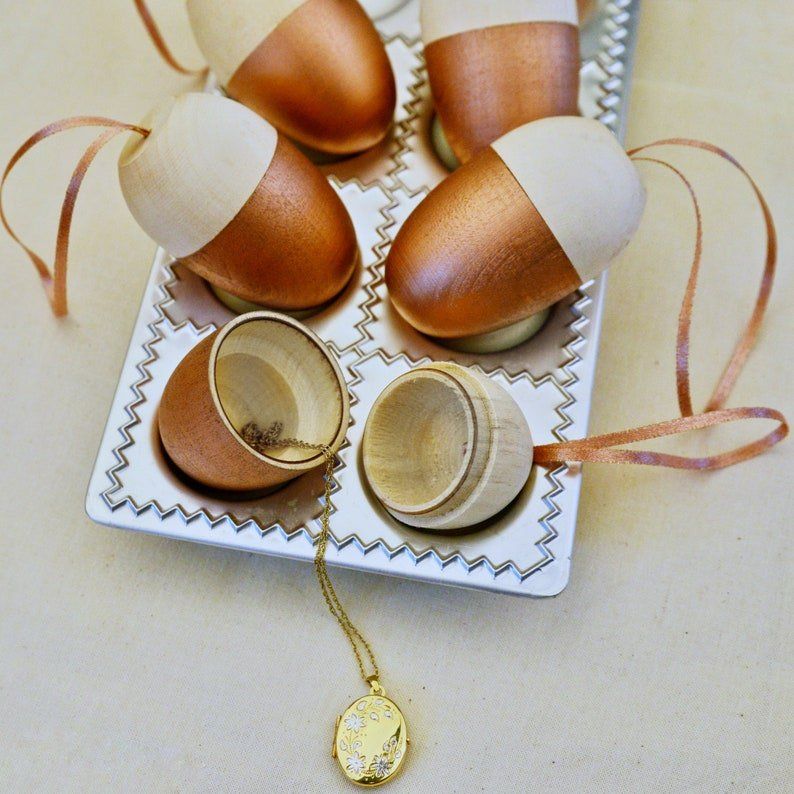 A tray of acorn christmas ornaments with ribbons and a necklace inside