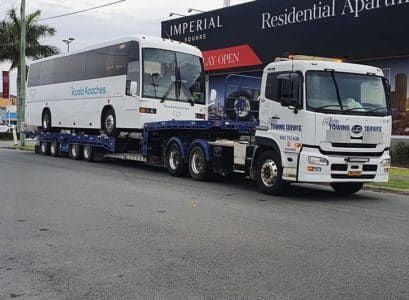 A Tow Truck With a Red Car on the Back — Mick’s Towing Service Pty Ltd in Carrara, QLD