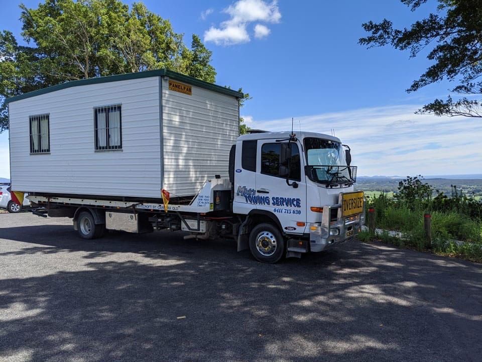 A Tow Truck With a Red Car on the Back — Mick’s Towing Service Pty Ltd in Carrara, QLD