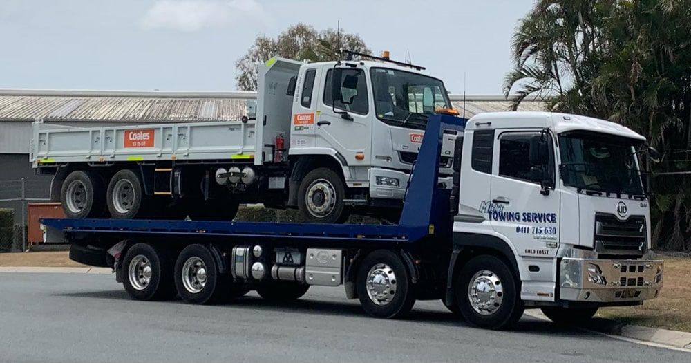 A Tow Truck With a Red Car on the Back — Mick’s Towing Service Pty Ltd in Carrara, QLD
