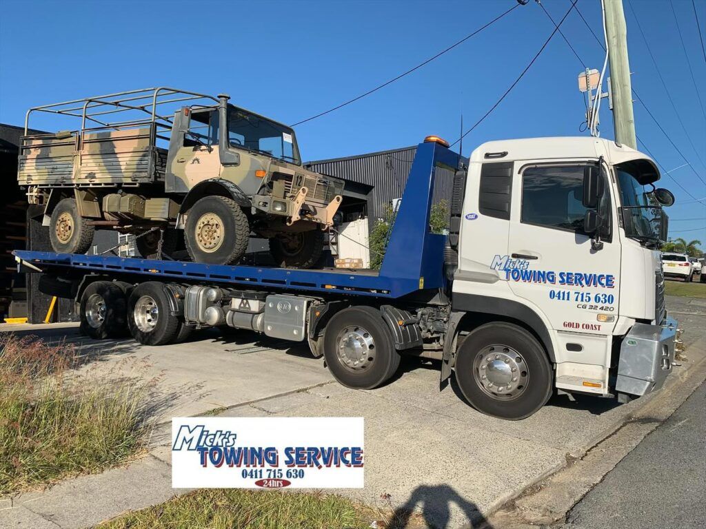 A Tow Truck With a Red Car on the Back — Mick’s Towing Service Pty Ltd in Carrara, QLD