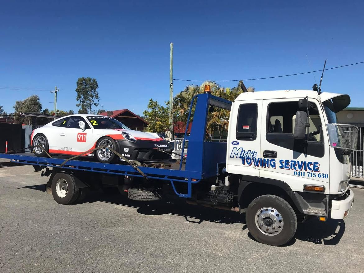 A Tow Truck with A Car on The Back of It — Mick's Towing Service Pty Ltd in Carrara, QLD