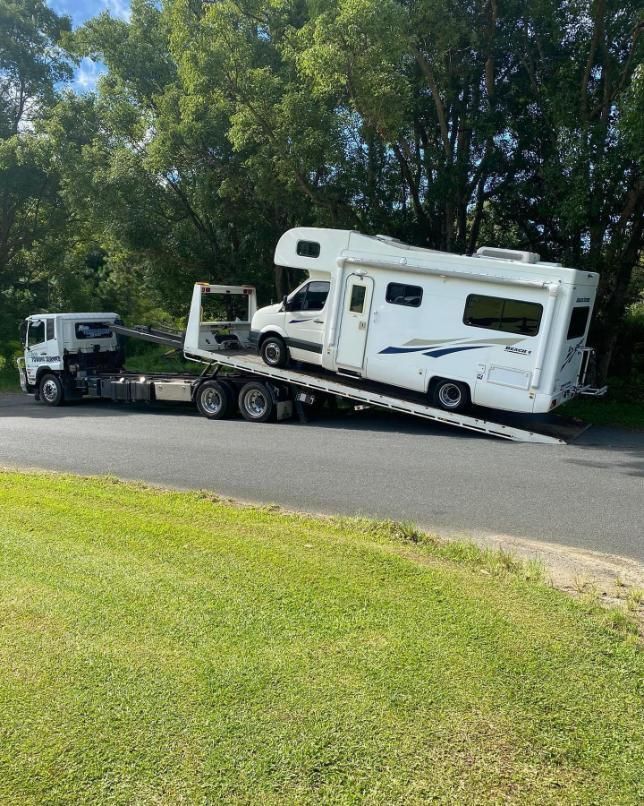 A Rv Is Being Towed by A Tow Truck Down a Road — Mick's Towing Service Pty Ltd in Carrara, QLD