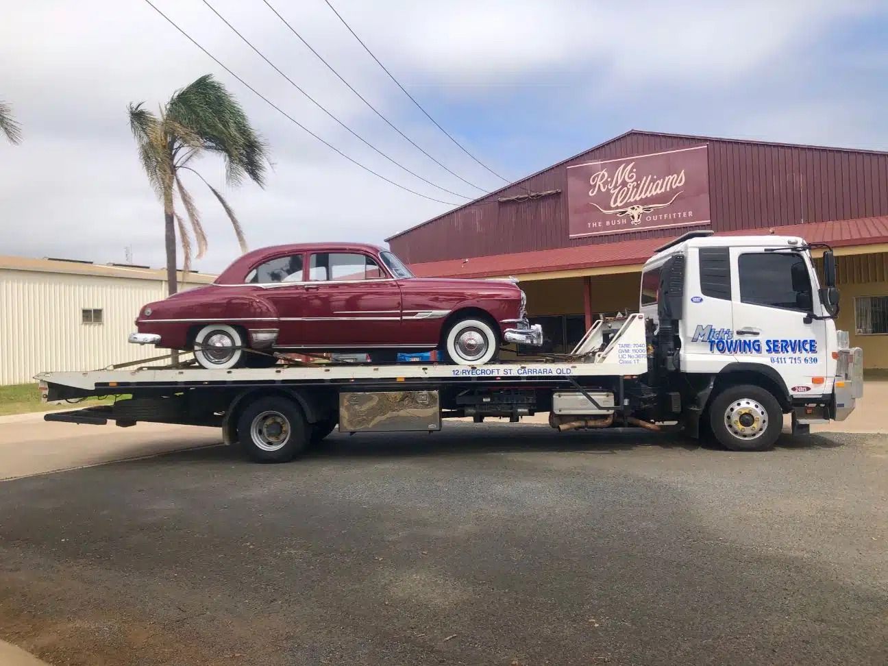 A Red Car is Being Towed by a Tow Truck — Mick's Towing Service Pty Ltd in Carrara, QLD