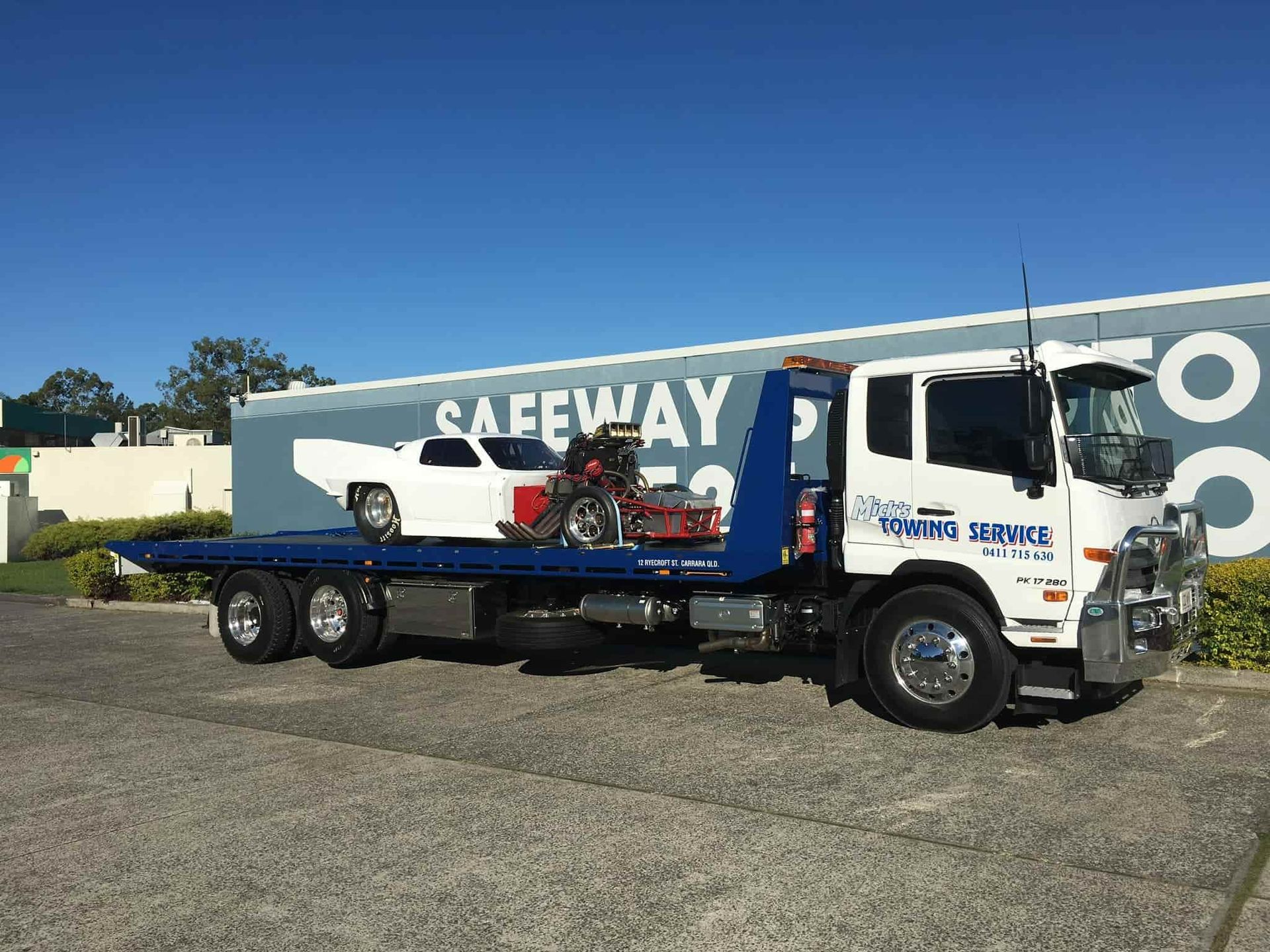 A Tow Truck is Towing a Car and a Motorcycle — Mick's Towing Service Pty Ltd in Carrara, QLD
