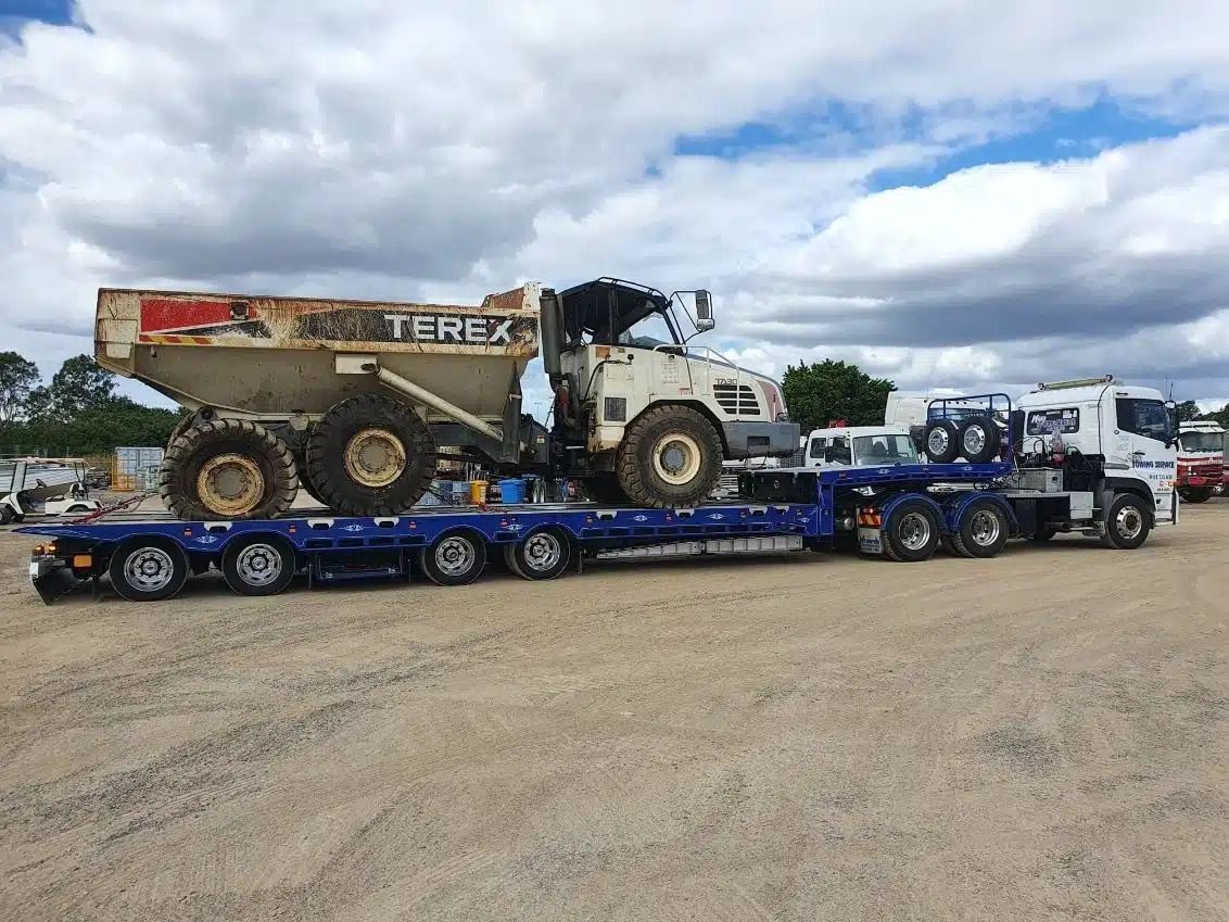 A Terex Dump Truck is Being Transported on a Flatbed Trailer — Mick's Towing Service Pty Ltd in Carrara, QLD