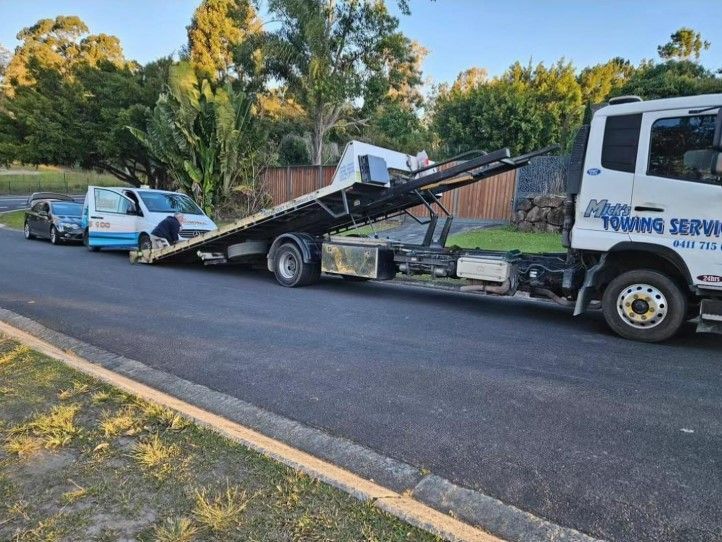 A Tow Truck With a Red Car on the Back — Mick's Towing Service in Carrara QLD