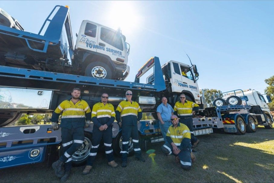A Tow Truck With a Red Car on the Back — Mick’s Towing Service Pty Ltd in Carrara, QLD