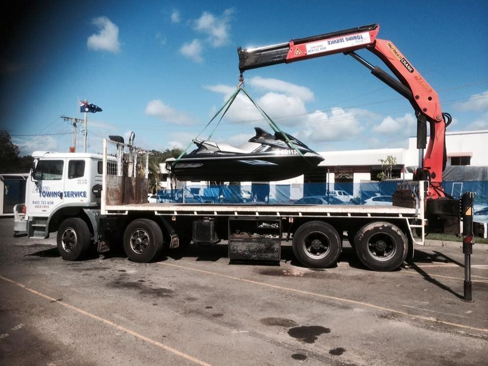 A Tow Truck With a Red Car on the Back — Mick’s Towing Service Pty Ltd in Carrara, QLD