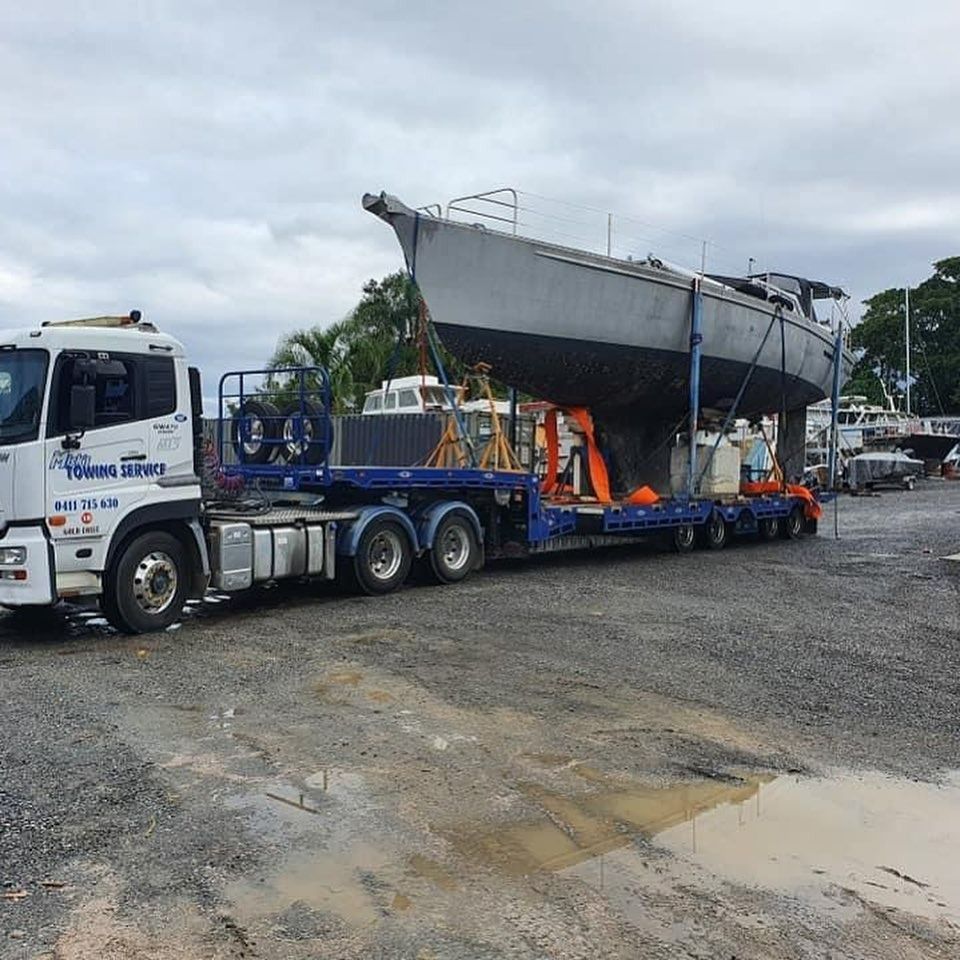 A Tow Truck With a Red Car on the Back — Mick’s Towing Service Pty Ltd in Carrara, QLD