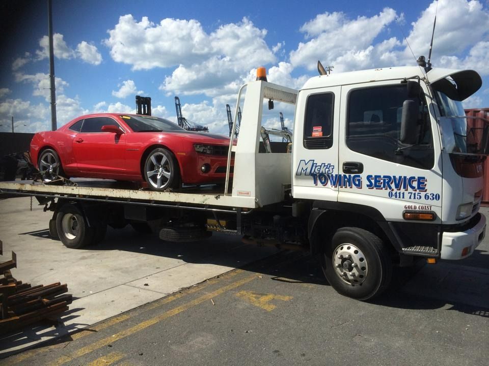 A Red Car is on the Back of a Towing Service Truck — Mick's Towing Service Pty Ltd in Carrara, QLD