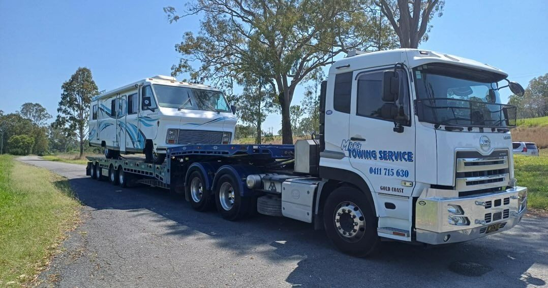 A Tow Truck With a Red Car on the Back — Mick’s Towing Service Pty Ltd in Carrara, QLD