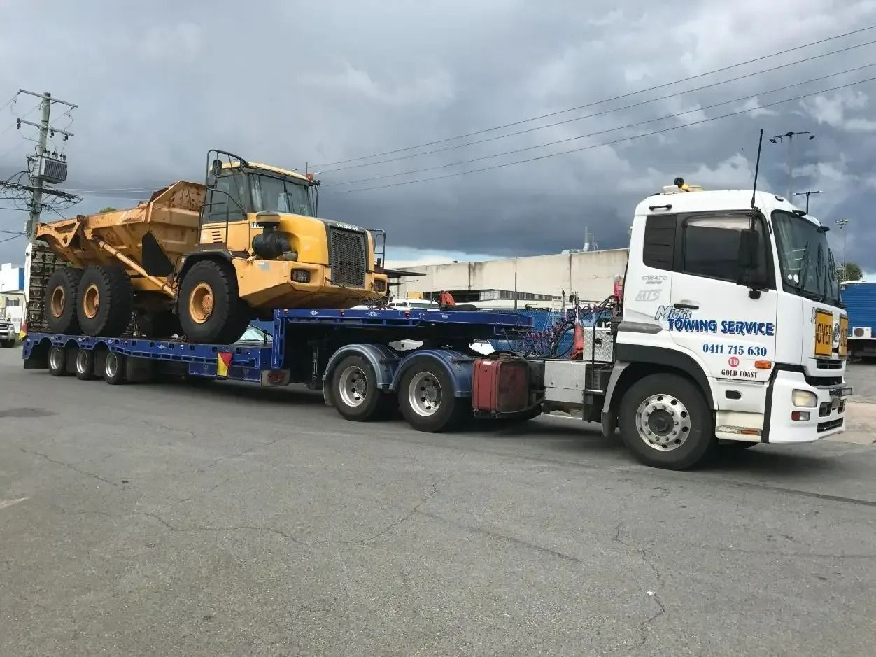 A Truck is Carrying a Bulldozer on a Trailer — Mick's Towing Service Pty Ltd in Carrara, QLD