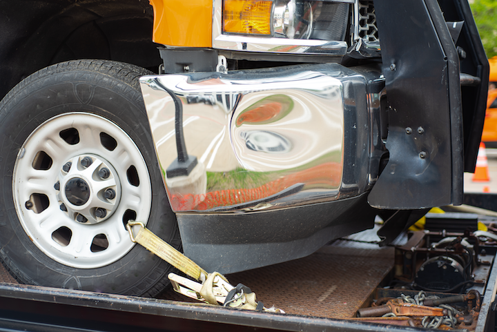 Heavy truck secured to the tilt tray of a tow truck.