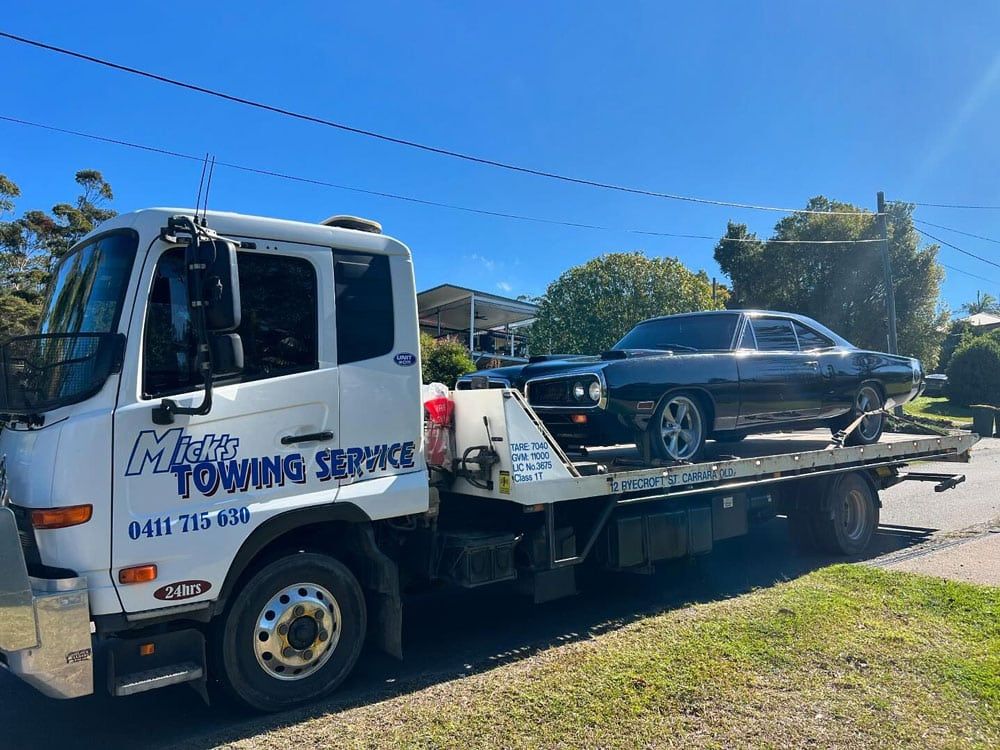 A Tow Truck With a Red Car on the Back — Mick’s Towing Service Pty Ltd in Carrara, QLD