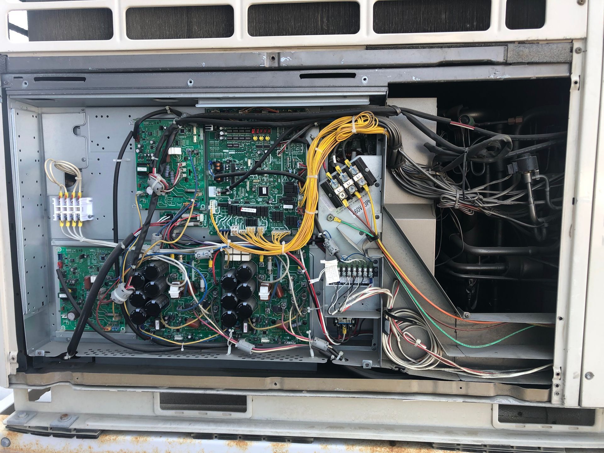 Open panel of Toshiba air conditioning unit reveals circuit boards and wiring.