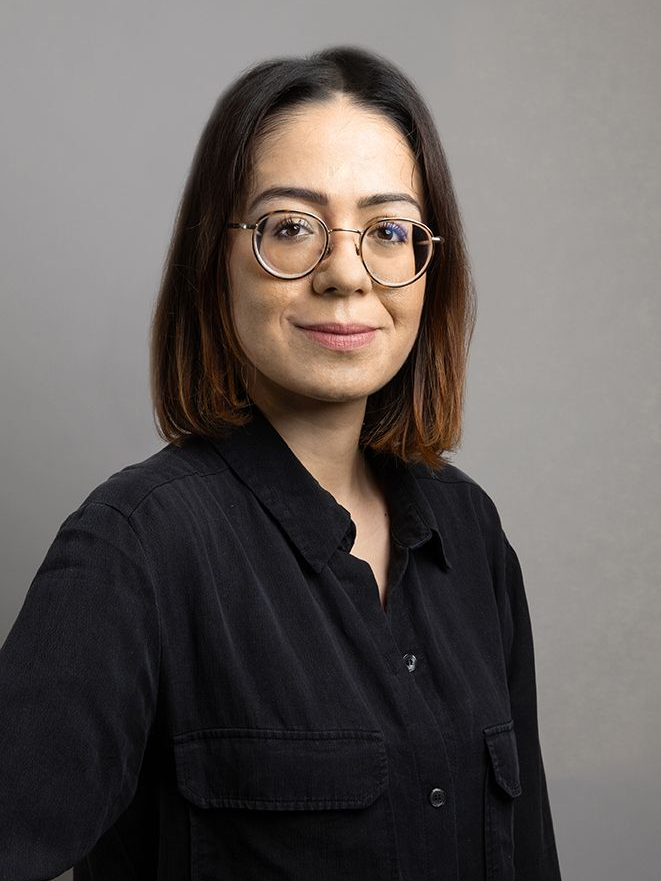 Une femme portant des lunettes et une chemise noire pose pour une photo.